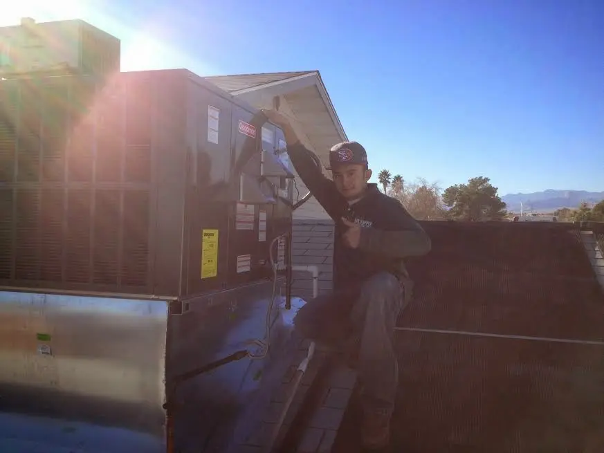 HVAC technician performing Air Duct Repair on a rooftop unit in Solvay